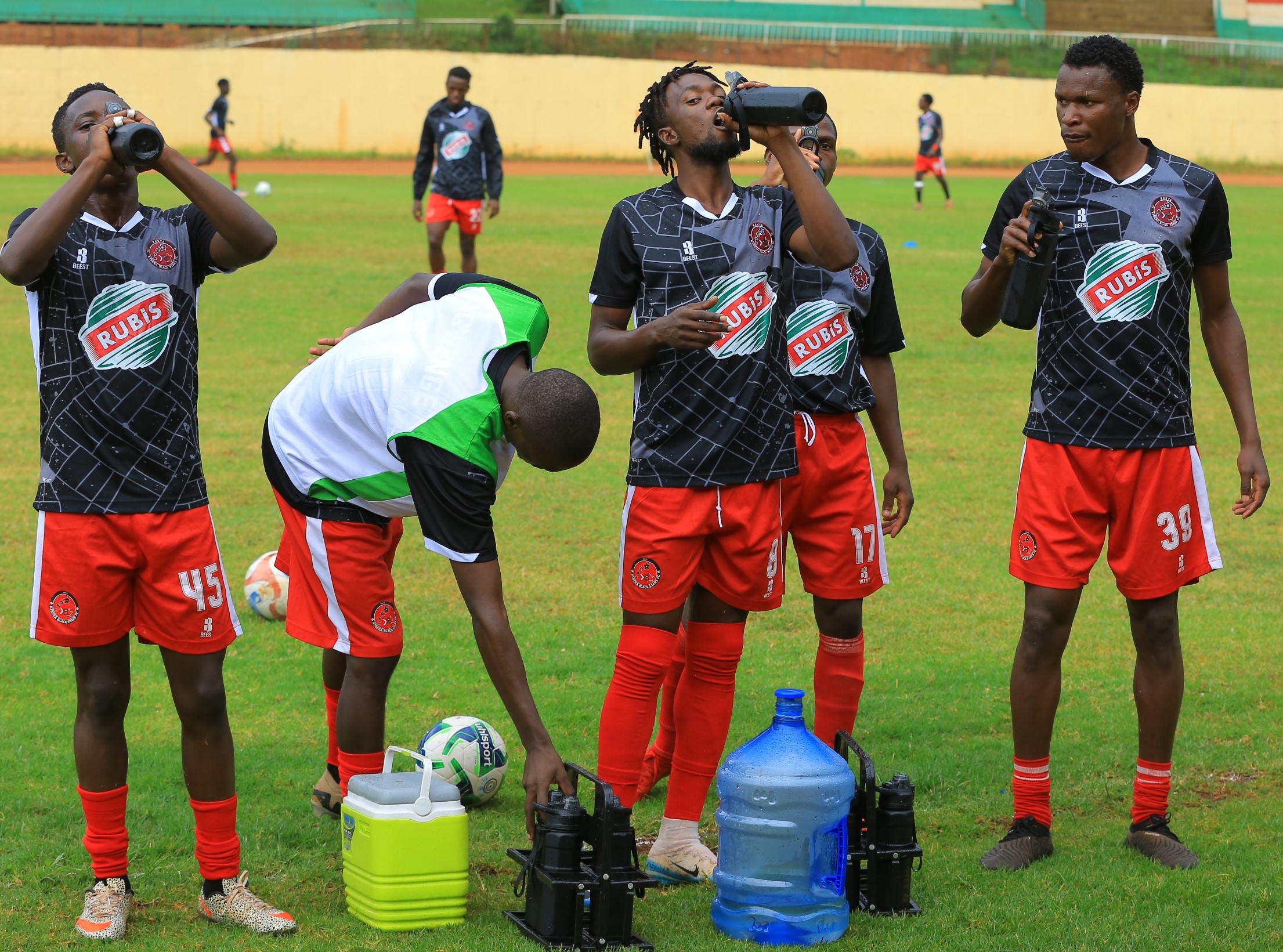 Kibera Black Stars players quench their thirst at Gusii Stadium