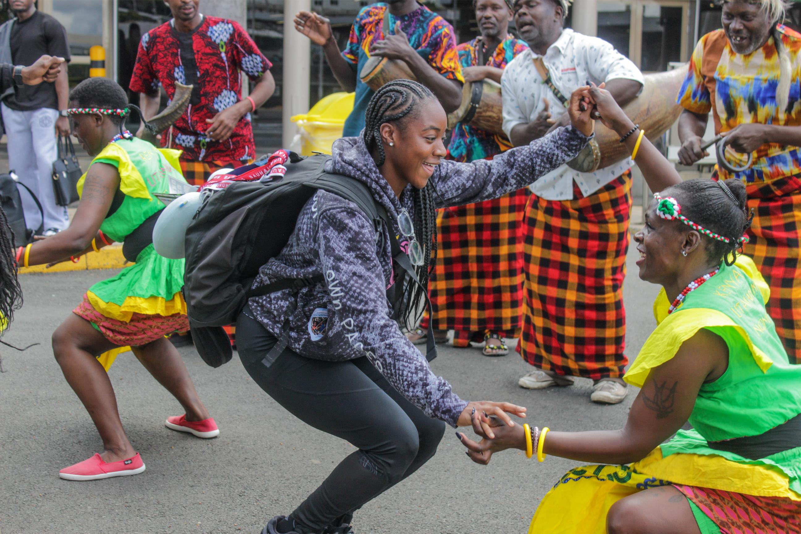 American Sprinter Chante Clinkscale dances with traditional dancers after arriving at JKIA