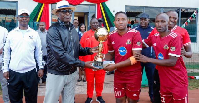 Kenya Prisons Service Commissioner General Patrick Aranduh (L) gives  atrophy to Dickson Kimanzi, captain of Eastern region football team/ HANDOUT
