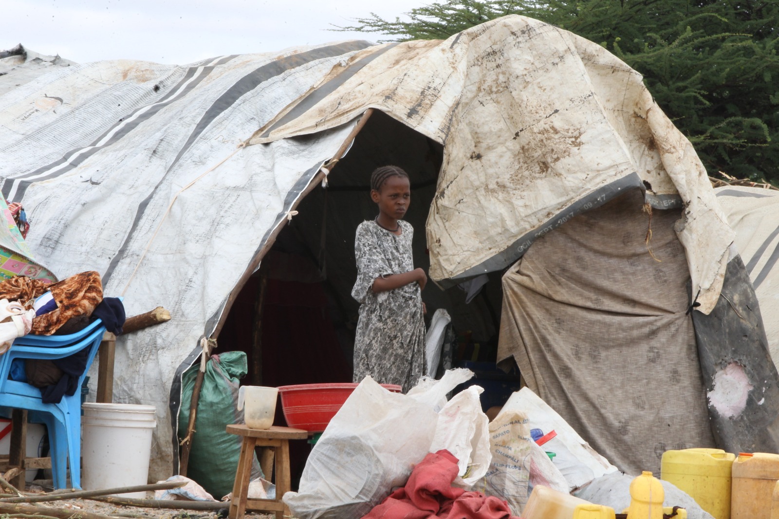 An internally displaced young girl from Mororo standing outside her family’s  makeshift tent at the Farmers Training Centre in Garissa.