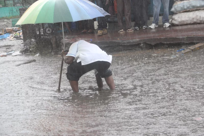 A man reaches for something in the water amid floods - FILE