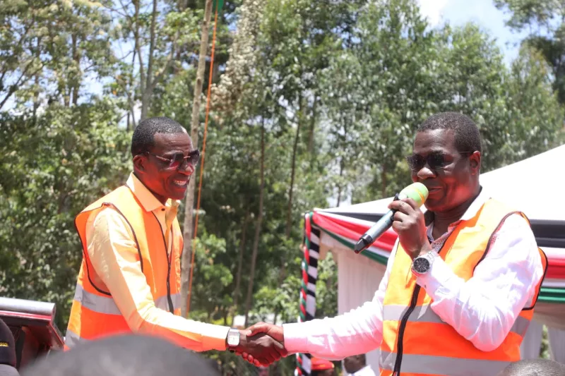 Malava MP David Ndakwa shake hands with Energy and Petroleum Cabinet Secretary Opiyo Wandayi during last mile connectivity of electricity in Malava on Monday/IMAGE/HILTON OTENYO