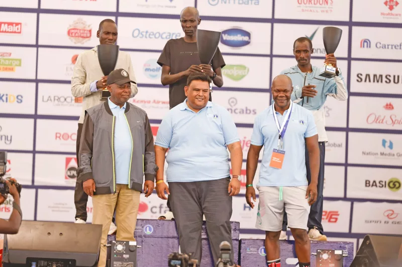 Podium finishers in the men’s 42km race at the Standard Chartered Nairobi Marathon 2026 display their trophies and dummy prize cheques presented by (front row from left) World Athletics Vice President and Athletics Kenya President Jackson Tuwei (Rtd), Standard Chartered CEO and Head of Coverage Birju Sangrajka, and Standard Chartered Nairobi Marathon Chairman David Mwindi/ HANDOUT
