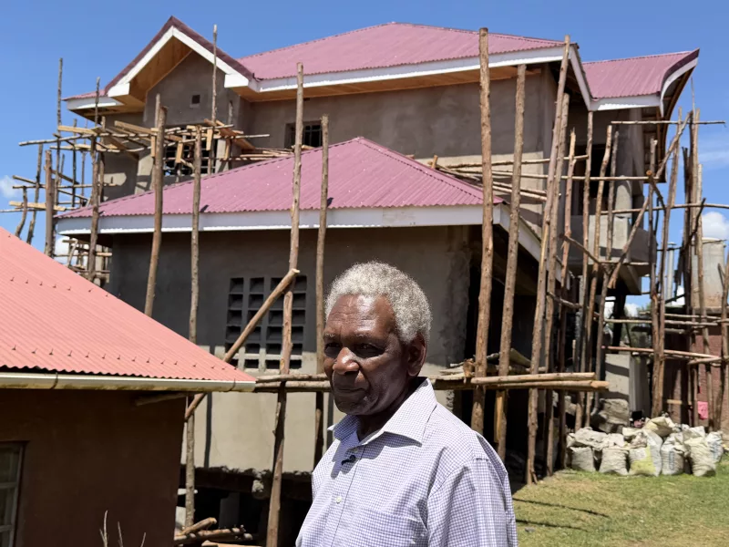 The pastor outside the church house he has developed using savings ane borrowing from Hustler Fund